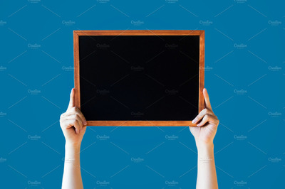 手持黑板图片素材 Human Hands Holding Empty Blank Black Board Over Blue Background - Ready for adding your text here